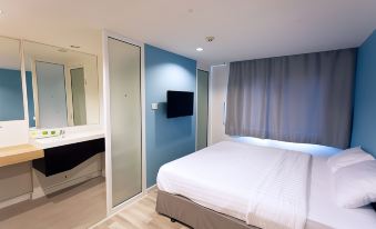 ห้องพัก Nantra Ploenchit Hotel ตกแต่งสะอาด ผนังสีน้ำเงิน เตียงขาว ทีวีติดผนัง