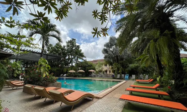 สระว่ายน้ำกลางแจ้งของ Park & Pool Resort ล้อมรอบด้วยเก้าอี้อาบแดดและสวนเขียว