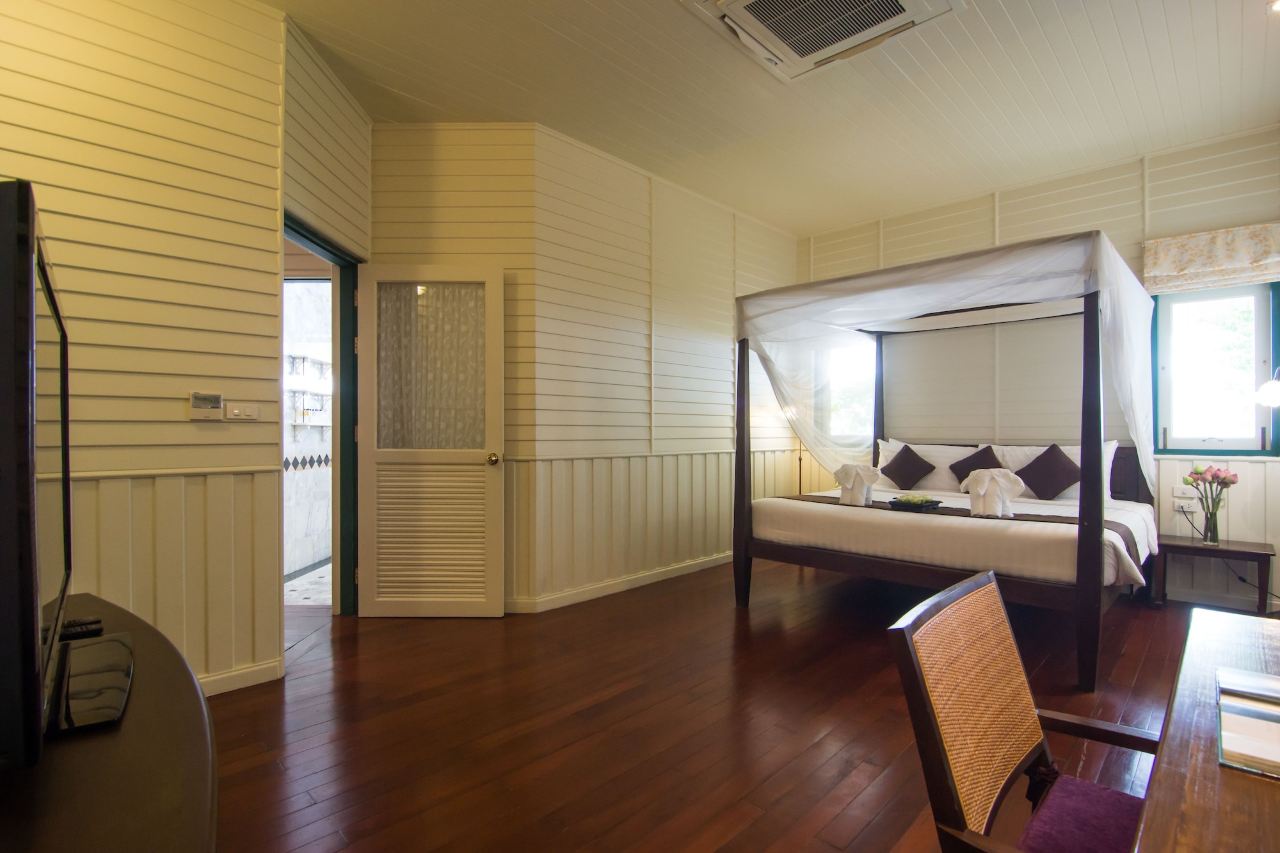 ห้องพักเรือนไม้สไตล์โคโลเนียลของ Kalanan Riverside Resort เตียงเสาสี่เสา พื้นไม้สีเข้ม