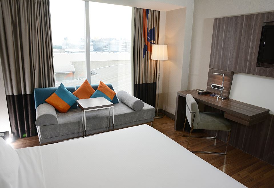 ห้องพักของ Novotel Bangkok IMPACT ตกแต่งโทนไม้-ขาว มีโซฟา เตียงนอนสบาย