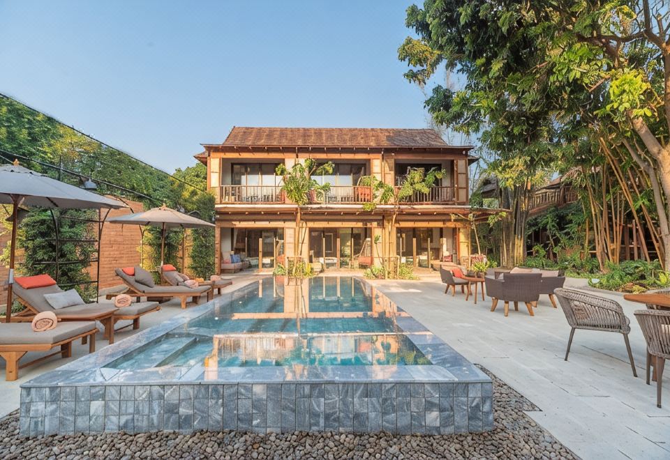 สระว่ายน้ำระบบน้ำอุ่นล้อมรอบด้วยสวนเขียวที่ Pai Village Boutique Resort ปาย