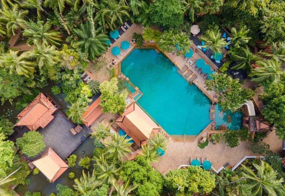 สระว่ายน้ำกลางสวนเขียวของ AVANI Pattaya Resort พร้อมสไลเดอร์และต้นไม้ใหญ่ร่มรื่น