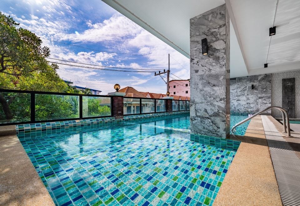 สระว่ายน้ำกลางแจ้งของ The Corner Lodge พัทยา ล้อมด้วยอาคารพักโทนอบอุ่นและสวนเล็ก