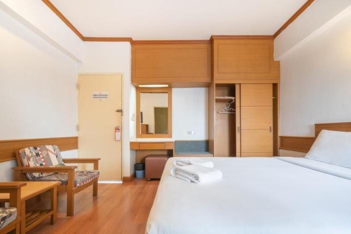 ห้องพัก Mike Hotel Pattaya มุมโต๊ะเครื่องแป้งและตู้เสื้อผ้าไม้ พร้อมโซฟานั่งเล่นในห้อง