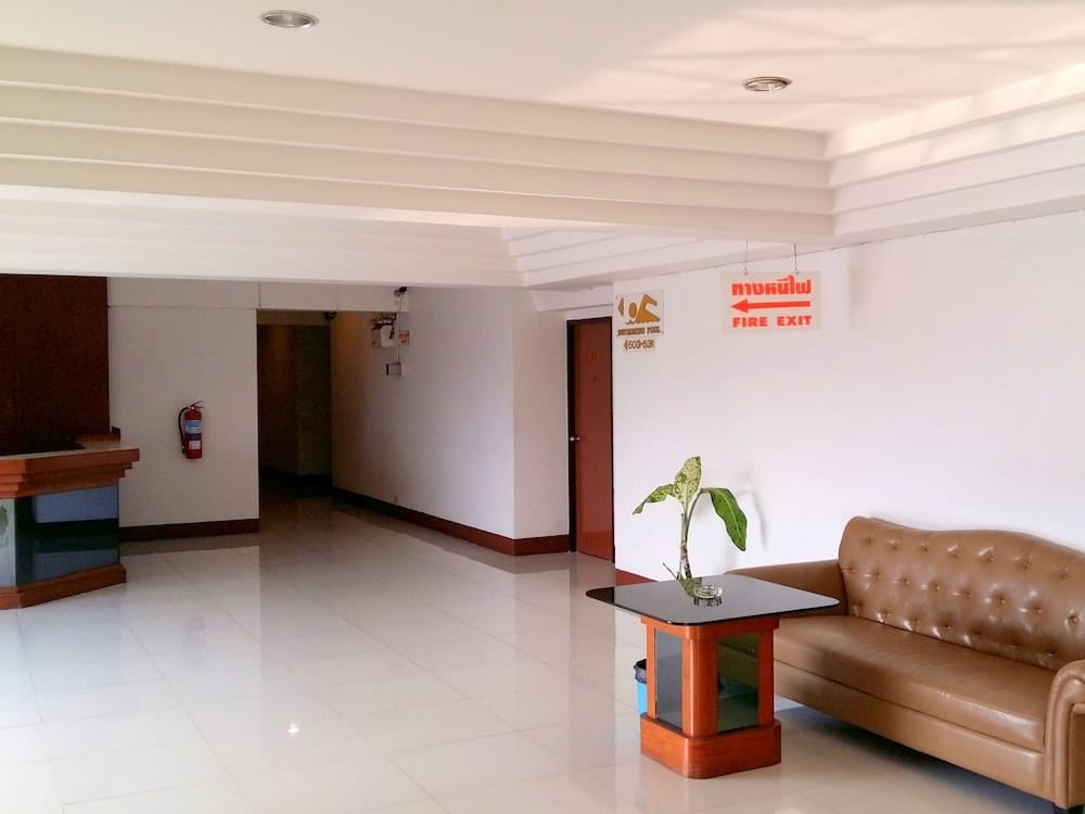 ล็อบบี้และโถงทางเดินของ Mike Hotel Pattaya ตกแต่งเรียบโทนขาว-ไม้ พร้อมป้ายทางหนีไฟและทางขึ้นสระ