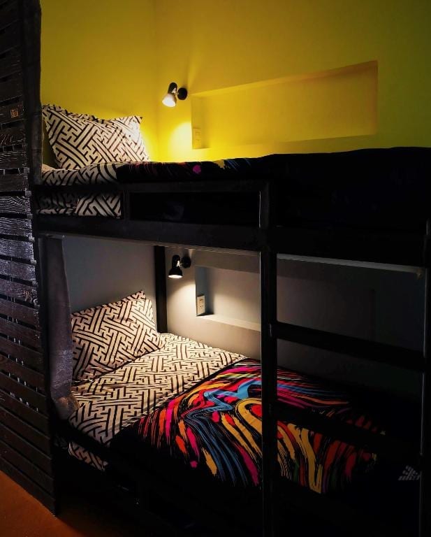 เตียงในห้องรวมปรับอากาศของ Qinglian Youth Hostel มีม่านทึบกั้นความเป็นส่วนตัวและปลั๊กไฟส่วนตัว