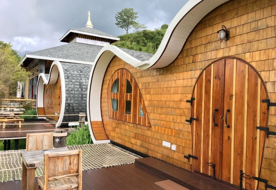 ห้องพักสไตล์ฮอบบิทของ Kiri Pura Resort เขาค้อ ผนังโค้งงานไม้พร้อมระเบียงวิวภูเขา