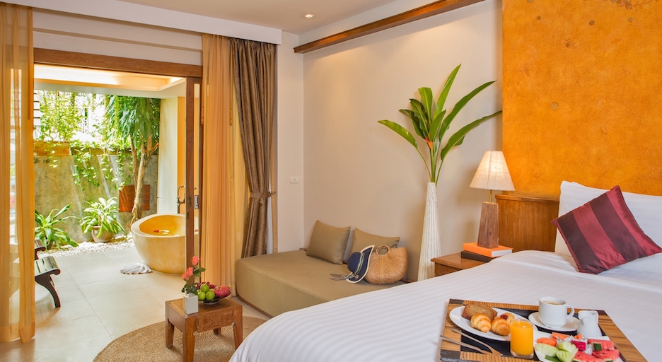 Honeymoon Room ของ Burasari Phuket พร้อมอ่างอาบน้ำกลางแจ้งในสวนส่วนตัวและถาดอาหารเช้าบนเตียง