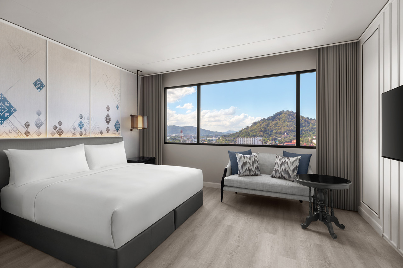 ห้องดีลักซ์ของ Courtyard by Marriott Phuket Town เตียงคิงพร้อมหน้าต่างบานใหญ่วิวเมืองเก่าและเขารัง