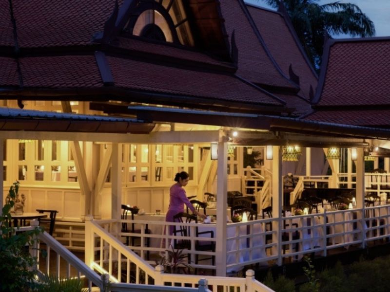 The teak pavilion of Benjarong restaurant at dusk, serving royal Thai cuisine by the lagoon at Dusit Thani Laguna Phuket