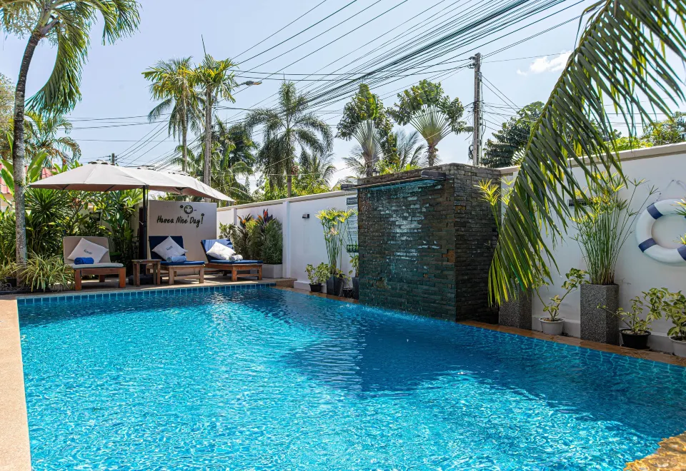 สระว่ายน้ำกลางแจ้งพร้อมน้ำตกในสวนเขตร้อนของ The Happy Eight Resort ภูเก็ต