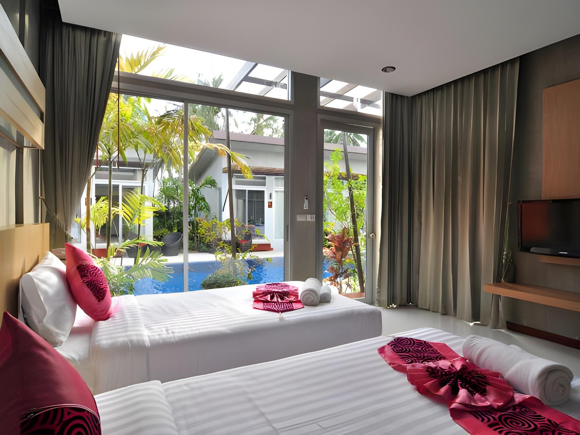 A pool-view room at Phu NaNa with twin beds and large glass doors opening onto the pool and tropical garden