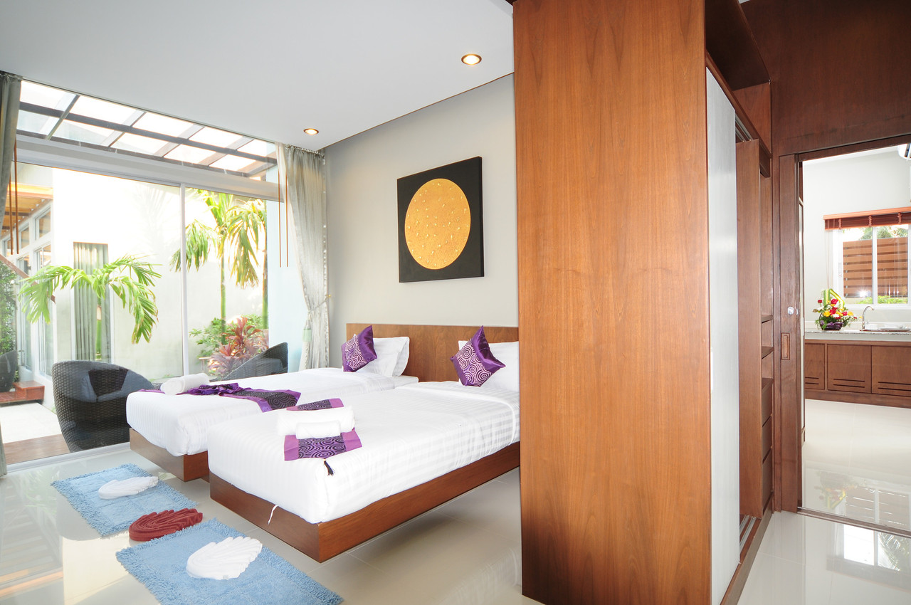 A family room at Phu NaNa with twin beds behind a wooden partition, opening to a small kitchen nook and garden terrace