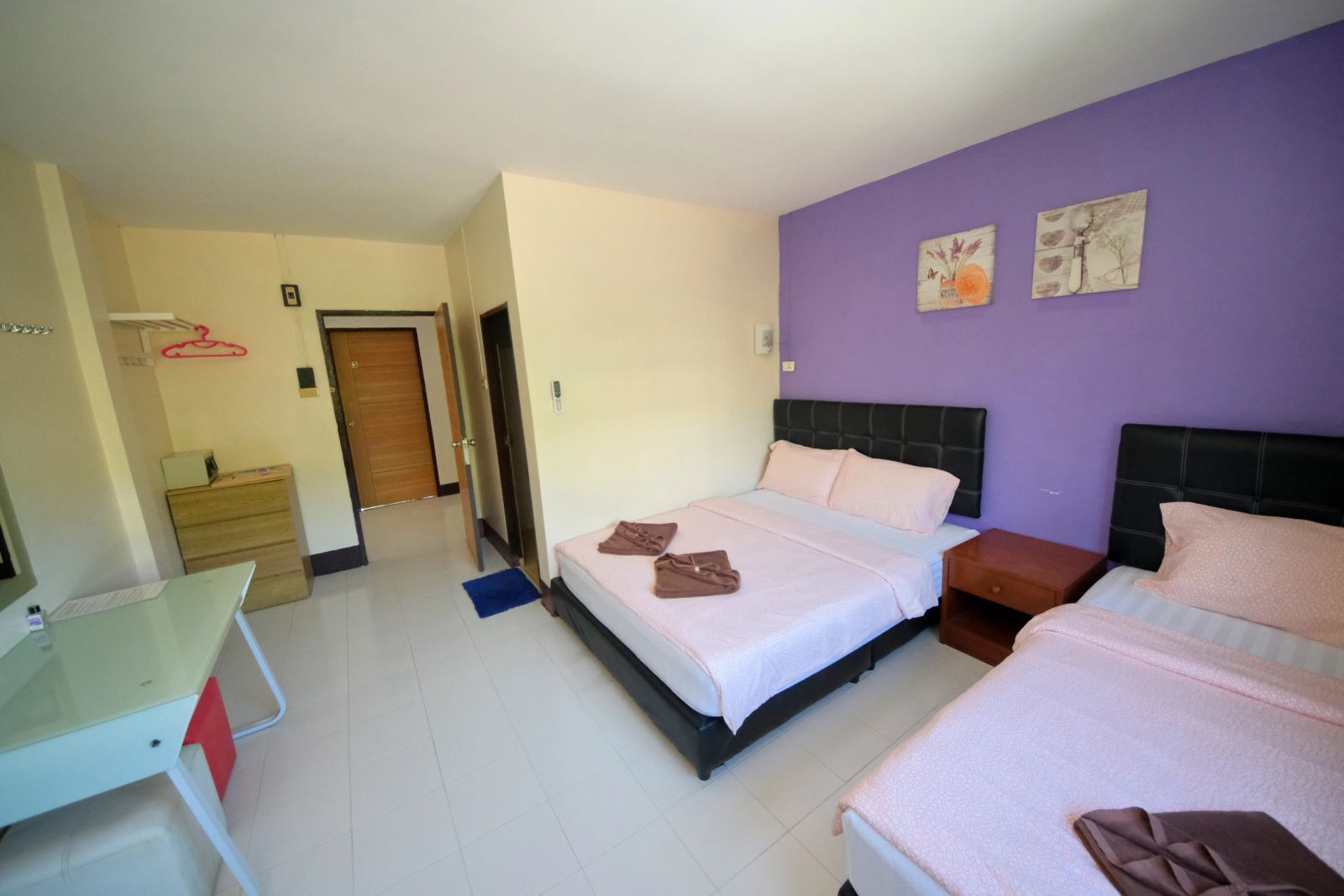 ห้อง Family Room ของ Pineapple Guesthouse ผนังสีม่วง สองเตียงพร้อมไมโครเวฟและโต๊ะ