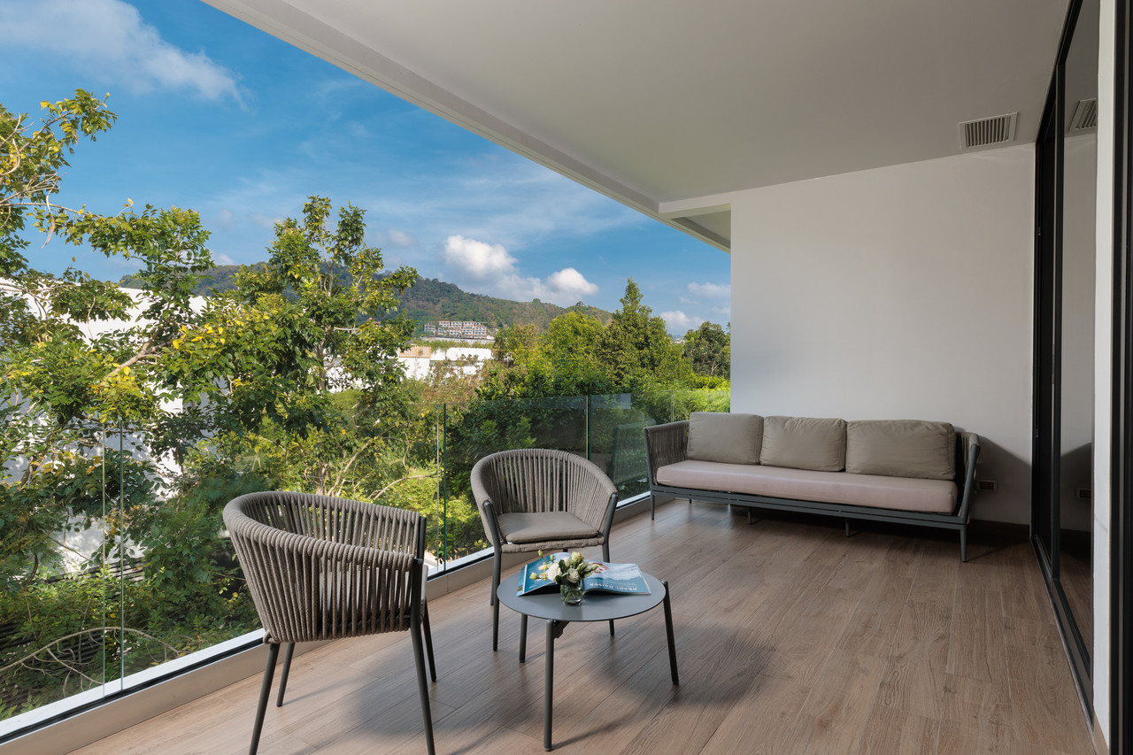 A suite balcony with a lounge corner and green hillside views at STAY Wellbeing & Lifestyle Resort, Phuket