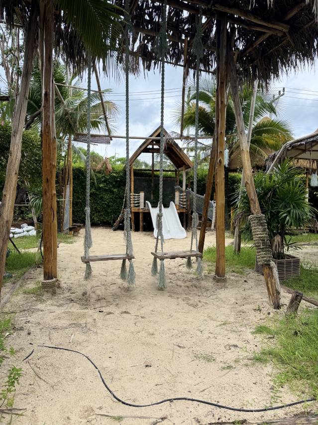 The garden play area at Sugar Marina ART with rope swings and a slide among the palm trees