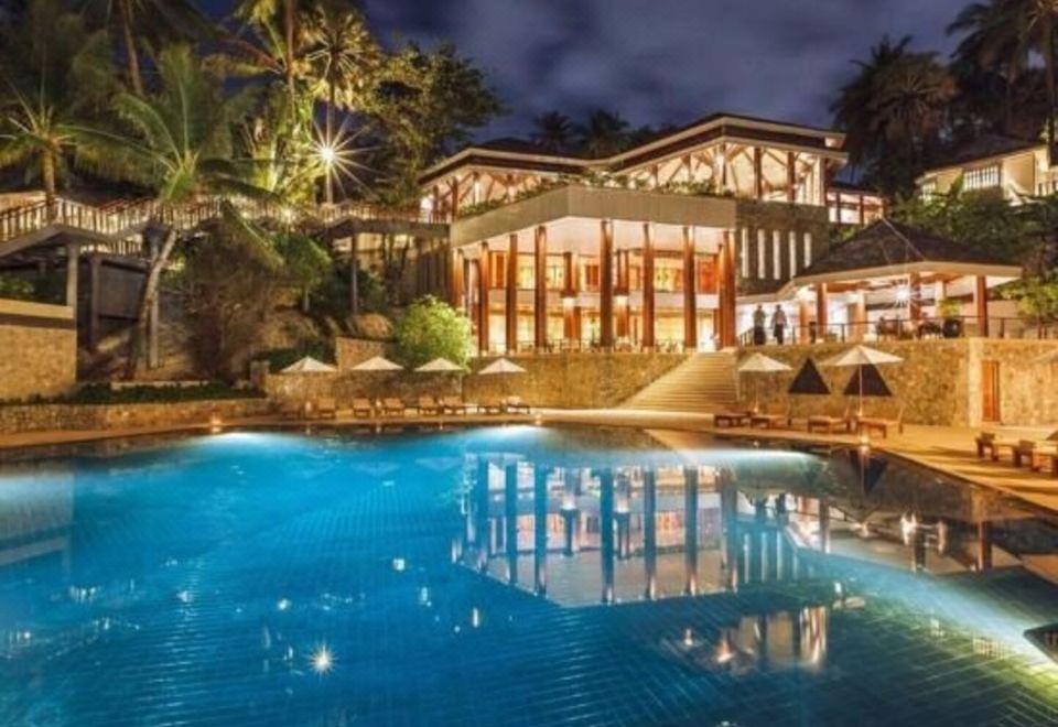 คอตเทจไม้ของ The Surin Phuket ตั้งอยู่ในดงมะพร้าวไล่ลงเนินสู่ทะเล