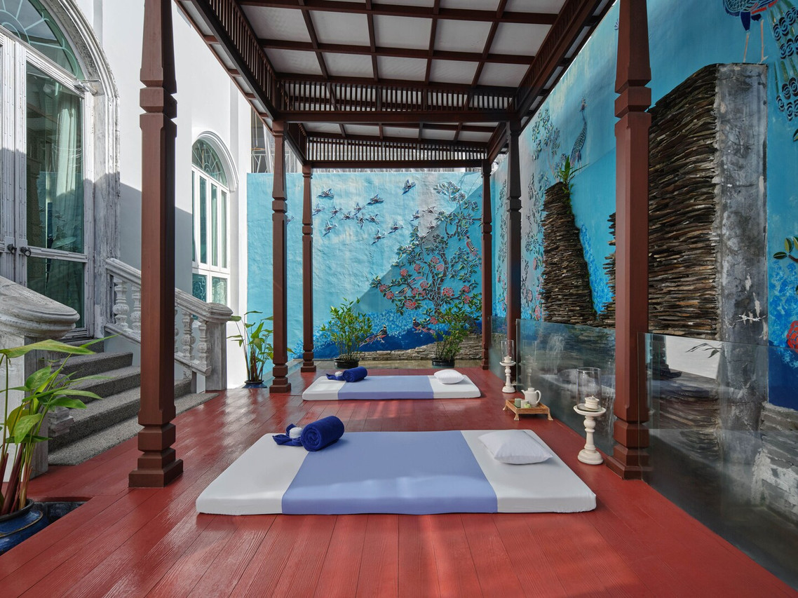ห้องทรีตเมนต์ของ The Kee Spa สไตล์ชิโน-โปรตุกีส หน้าต่างโค้งสูงและภาพวาดนกยูงบนผนัง