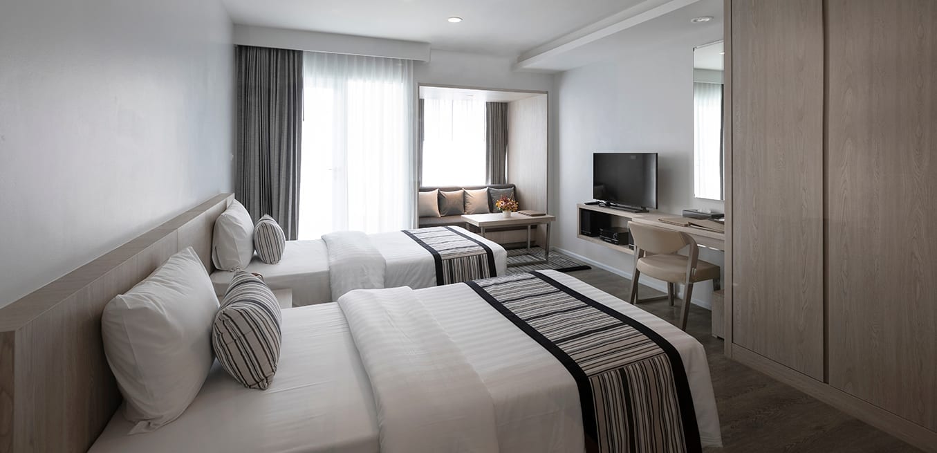 ห้อง Deluxe เตียงคู่ของแคนทารี 304 ปราจีนบุรี โทนสว่างสะอาด มีโต๊ะทำงานและโซฟา