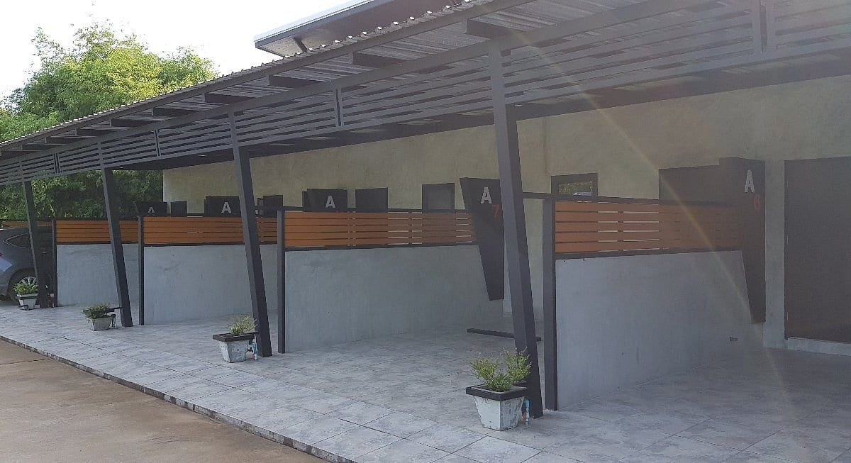 อาคารและป้าย The Loft Resort Kabin Buri ปราจีนบุรี สไตล์ลอฟท์ปูนเปลือยโทนเทา-ดำตัดตัวอักษรสีส้ม