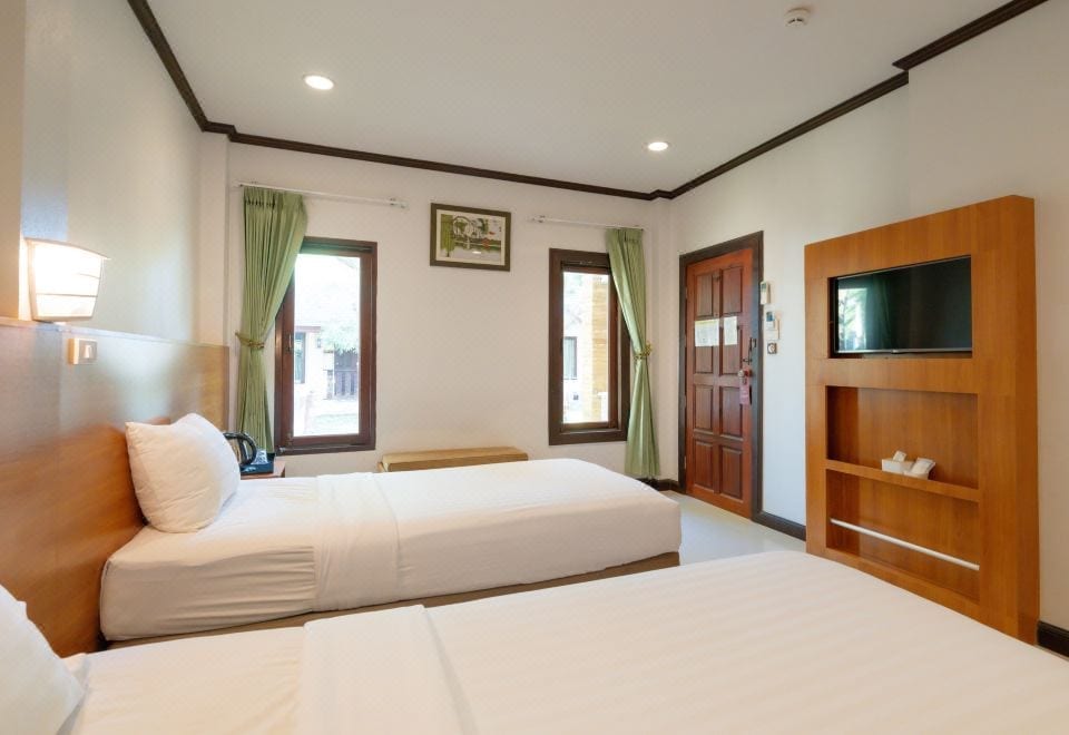 สระว่ายน้ำใหญ่กลางแจ้งของ The Green Beach Resort พร้อมพื้นที่นั่งเล่นริมสระท่ามกลางสวนเขียว