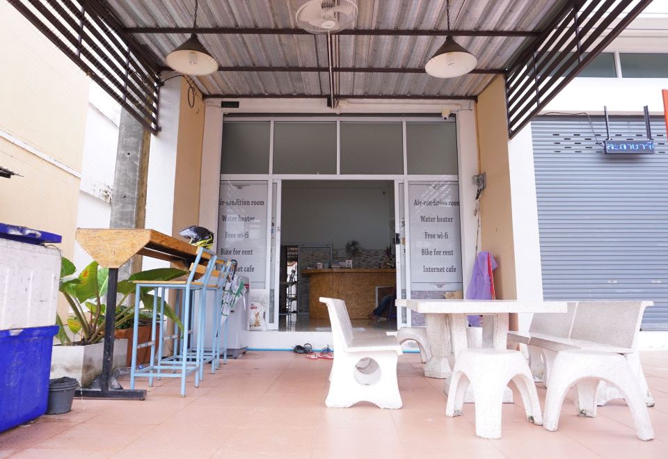 หน้าโฮสเทล Ranong Backpacker's Hostel ระนอง มีที่นั่งหินและป้ายบริการห้องแอร์ น้ำอุ่น Wi-Fi ฟรี เช่าจักรยาน