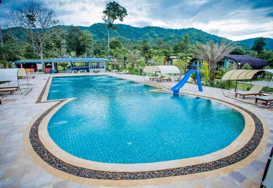 สระว่ายน้ำใหญ่กลางสวนของ The Banyan Leaf Resort สวนผึ้ง ราชบุรี ล้อมด้วยทิวเขาและต้นไม้ร่มรื่น