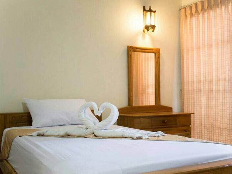 ห้องพักของ Veerasuda Condotel ราชบุรี ตกแต่งด้วยเฟอร์นิเจอร์ไม้สัก โทนอบอุ่น เตียงสะอาด