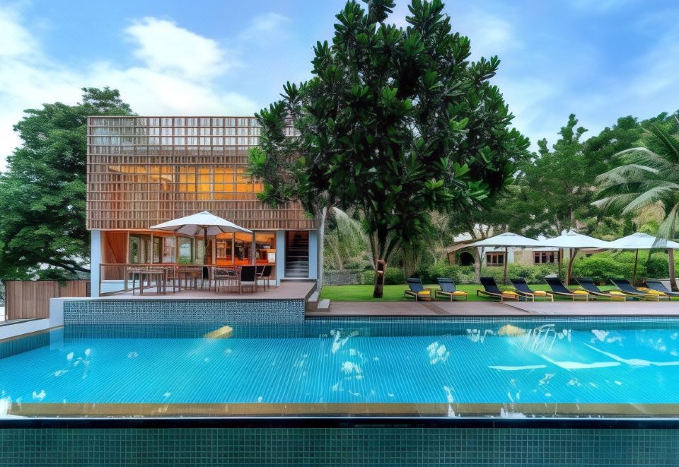สระว่ายน้ำกลางแจ้งริมหาดของ Centara Q Resort Rayong มองออกไปเห็นทะเลหาดแม่พิมพ์