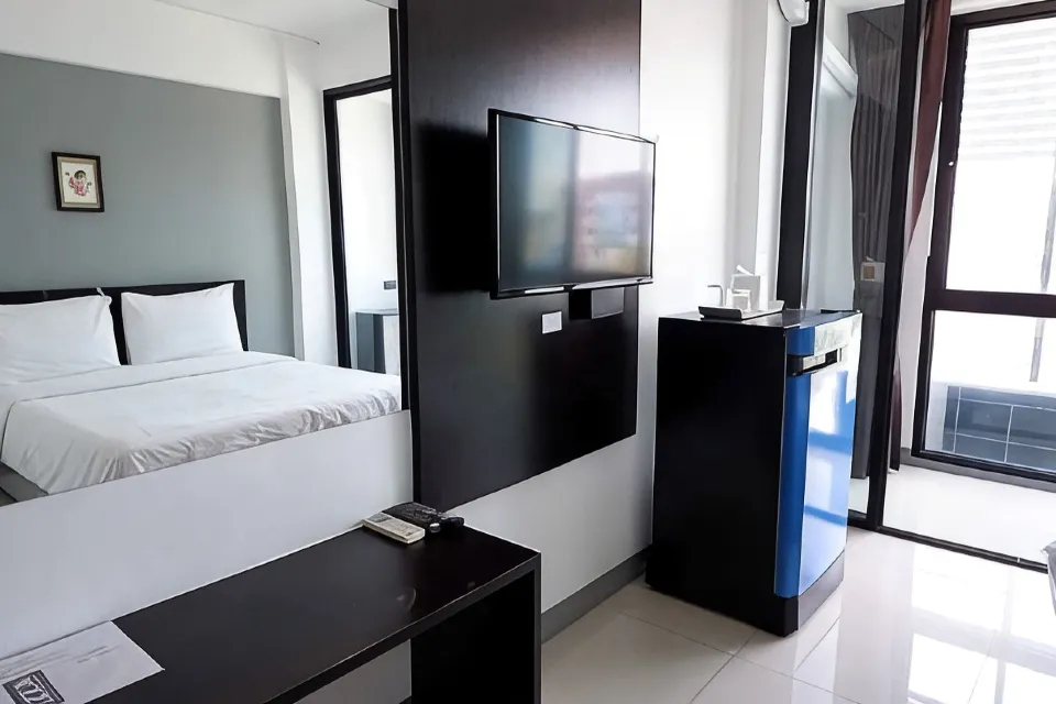 ห้องพักปรับอากาศของ IZEN Budget Hotel Rayong ตกแต่งเรียบโทนสว่าง เตียงนอนและโต๊ะข้างเตียง