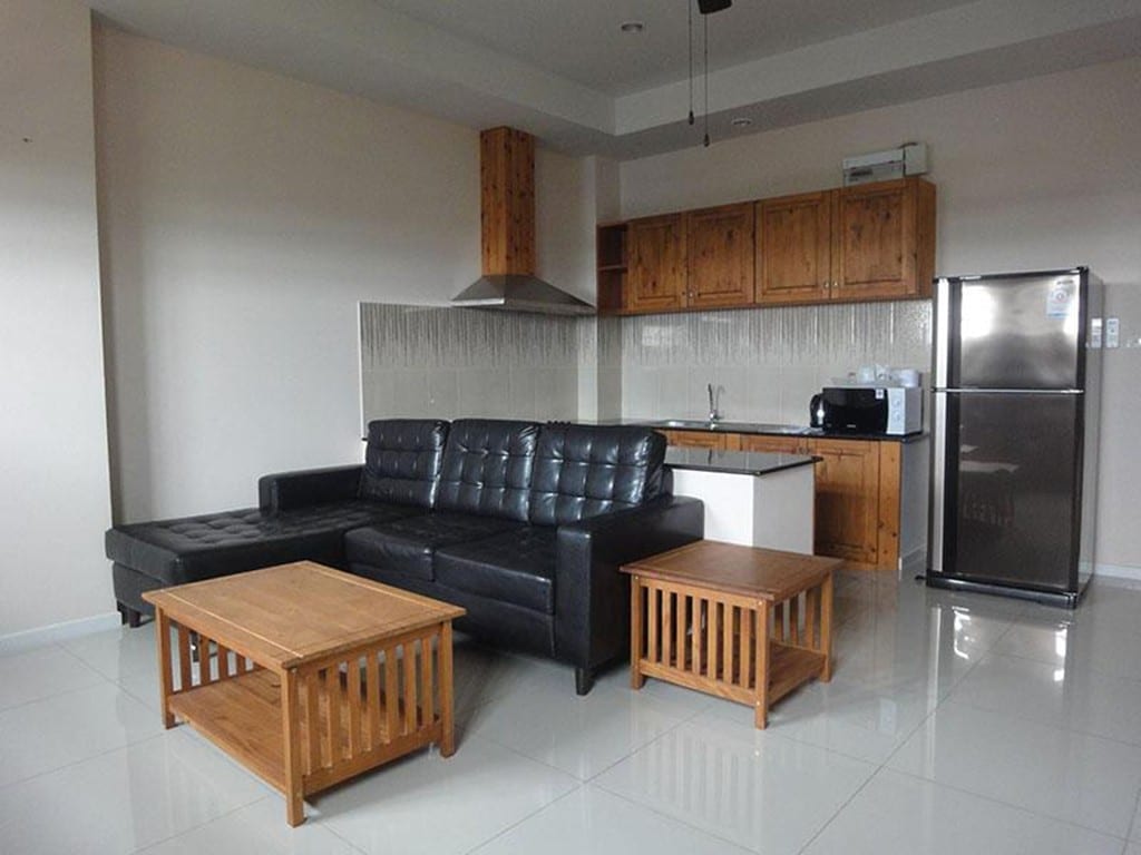 ห้องพักของ Royal Place Banchang ตกแต่งโทนอบอุ่น มีเตียงใหญ่ ตู้เย็น และโต๊ะทำงาน