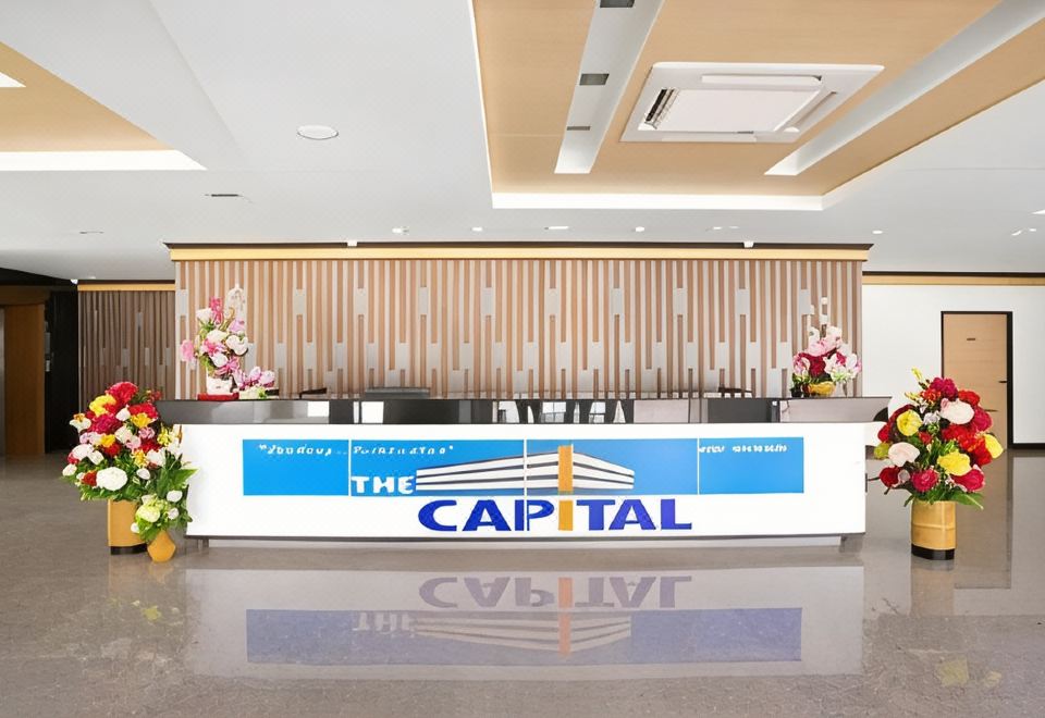 ห้องพักของ The Capital Hotel ร้อยเอ็ด เตียงคู่ สะอาด พร้อมโต๊ะและเก้าอี้นั่งมองวิว