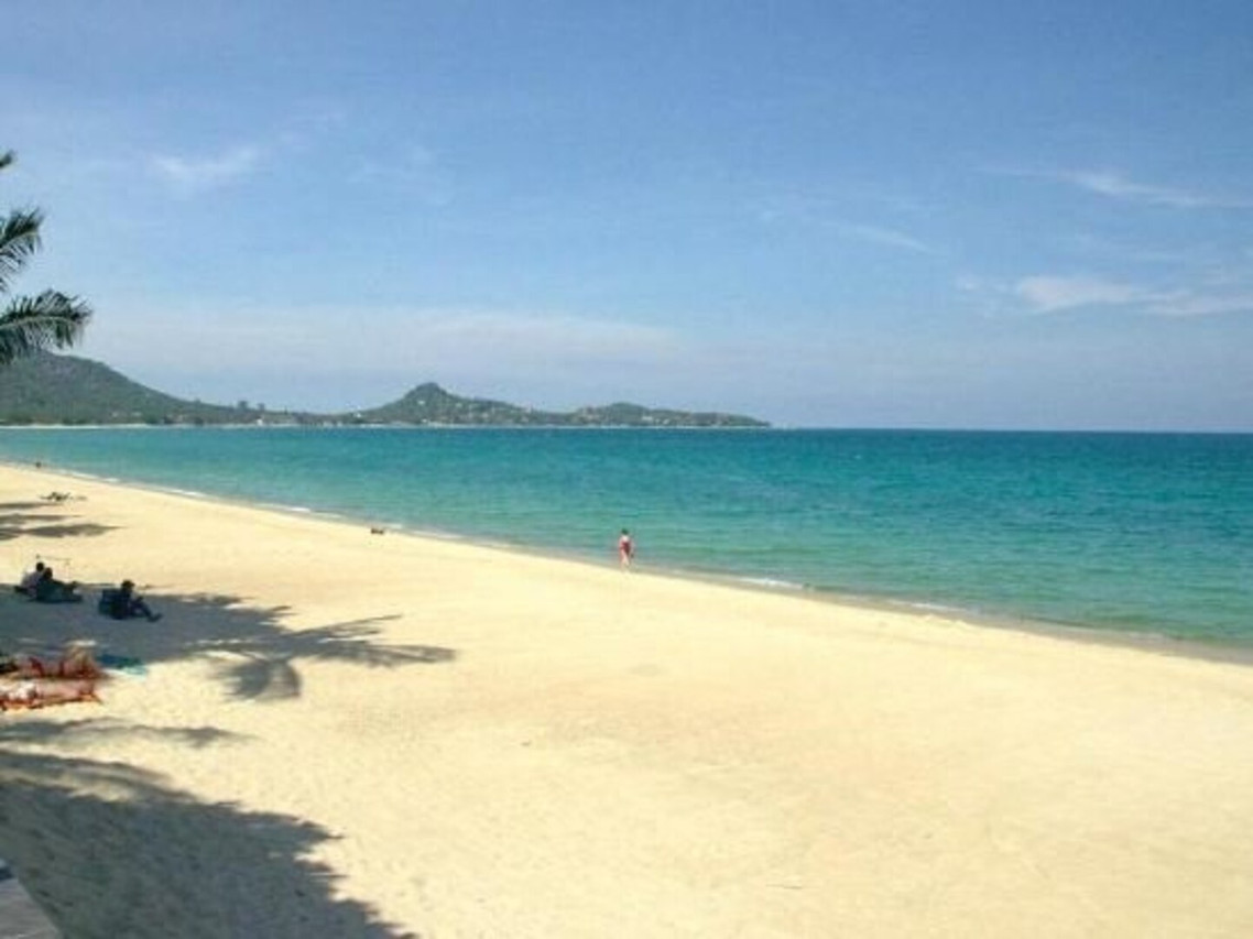 หาดทรายขาวและน้ำทะเลสีเทอร์คอยซ์ของหาดละไมมองเห็นแหลมไกล ๆ ที่ Aloha Resort เกาะสมุย