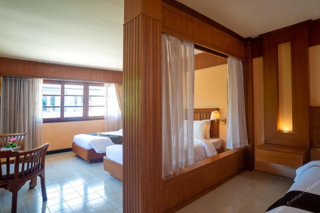 ห้องพักสไตล์ไทยไม้สักของ Aloha Resort เตียงมีผ้าม่านมุ้ง พื้นกระเบื้อง และระเบียงส่วนตัว