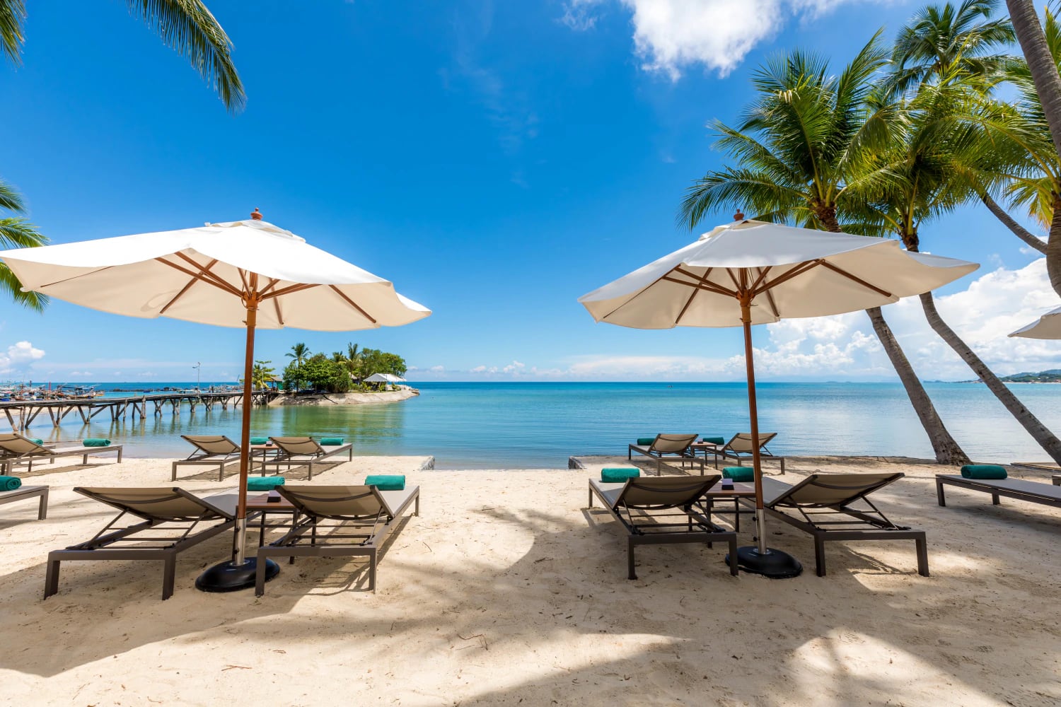 The Lamai beachfront in front of Outrigger Koh Samui with loungers and umbrellas looking out over the bay