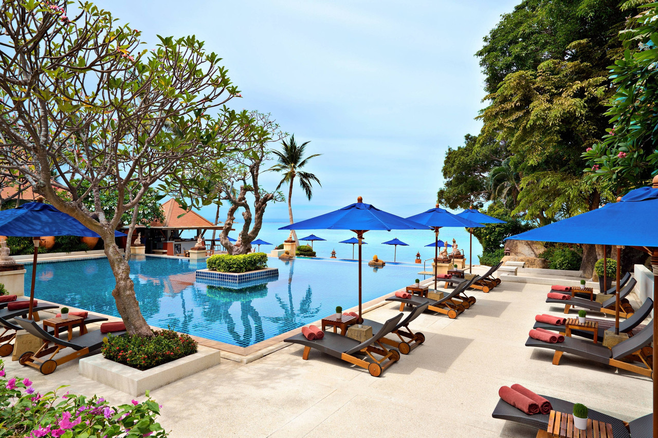 The beachfront infinity pool at Renaissance Koh Samui framed by orange-roofed Thai pavilions and tropical gardens looking out over Lamai Bay