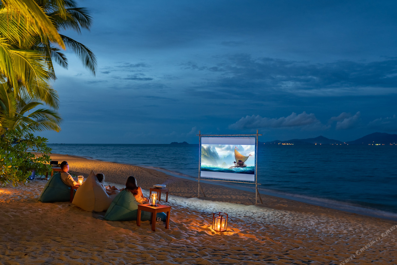 หนังกลางแปลงริมหาดยามค่ำของ Santiburi Koh Samui บนหาดทรายพร้อมโคมไฟและเก้าอี้บีนแบ็ก