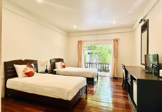 ทางเดินไม้และต้นไม้ใหญ่ในสวนของ Tree House Hotel ศรีสะเกษ ให้บรรยากาศร่มรื่น