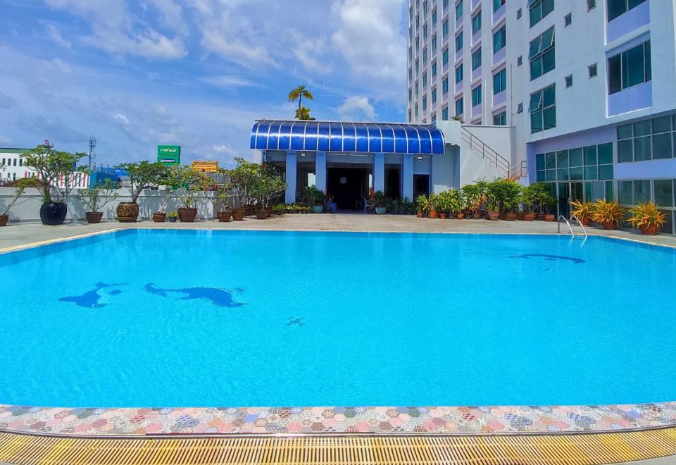 สระว่ายน้ำกลางแจ้งของ Diamond Plaza Hotel สุราษฎร์ธานี น้ำสีฟ้าใส มีสระเด็กและกระถางต้นไม้รอบสระ