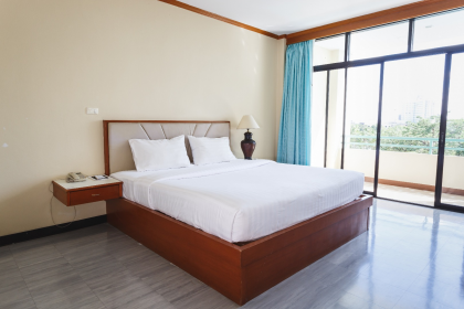 ห้องพักของ Surin Majestic Hotel เตียงกว้าง โทนสีอบอุ่น มองออกไปเห็นสระว่ายน้ำ