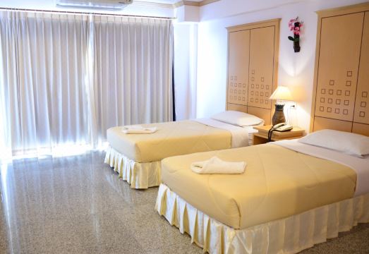 ห้องพักของโรงแรมมณีโรจน์ สุรินทร์ ห้องกว้างสะอาด เตียงนุ่ม โทนสีอบอุ่น พร้อมโต๊ะทำงานยาว