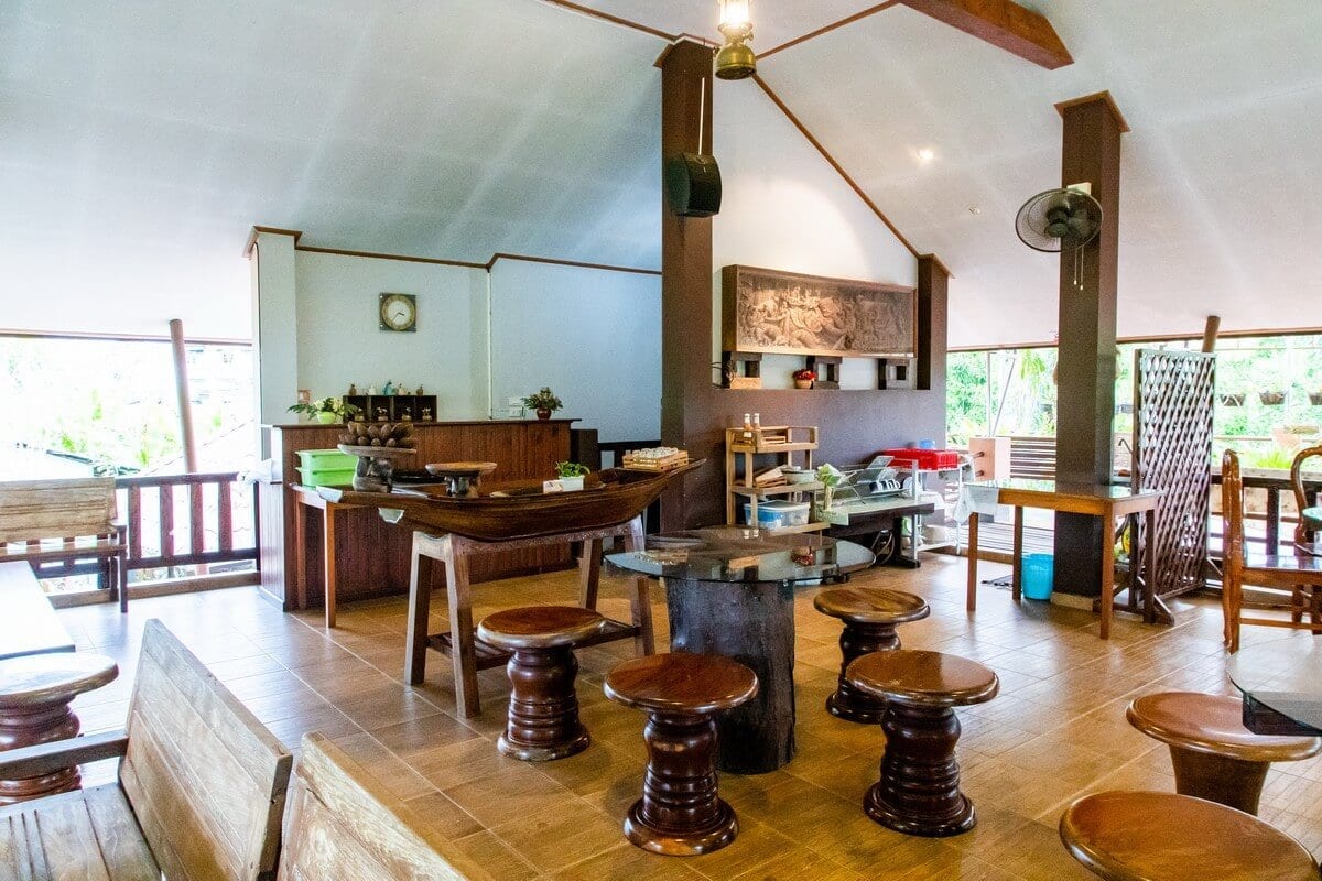 ห้องพักของ BaanRimNam Resort Trat มีประตูกระจกบานใหญ่เปิดออกระเบียงเห็นต้นไม้เขียวริมคลอง