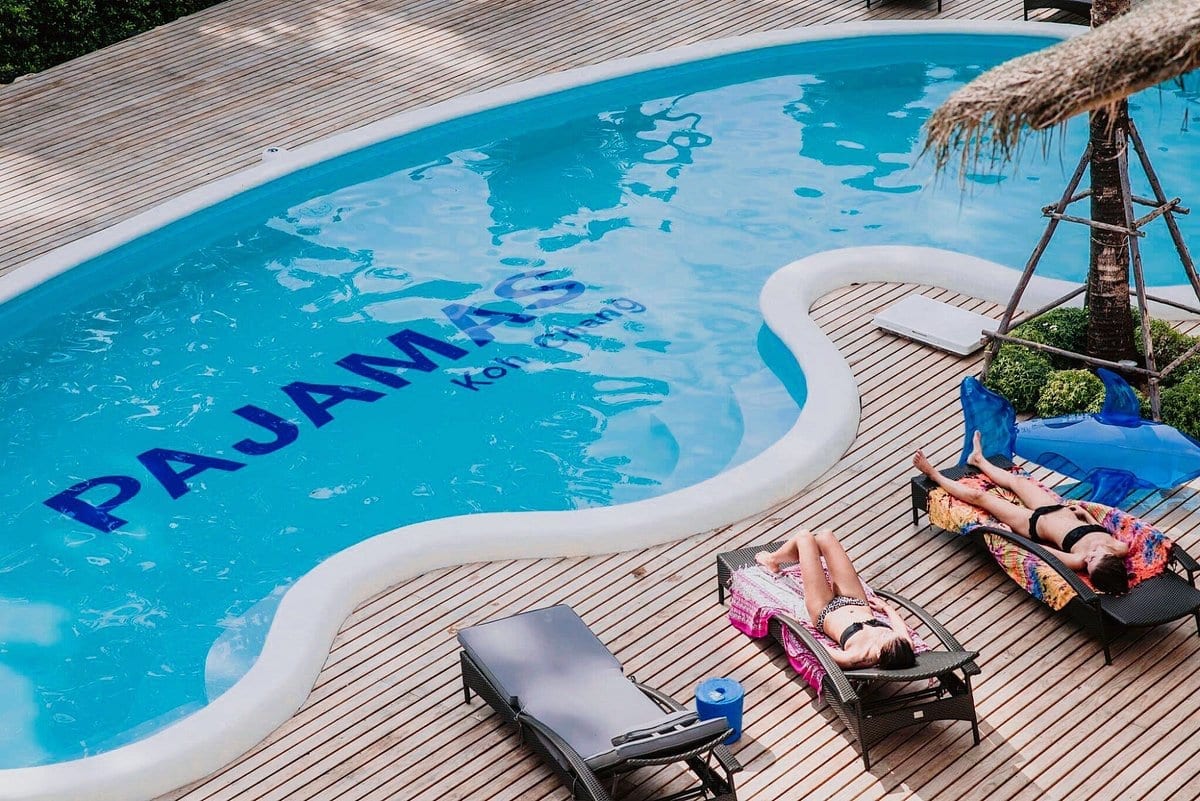สระว่ายน้ำกลางคอร์ตของ Pajamas Koh Chang ล้อมรอบด้วยห้องพักและเตียงอาบแดด