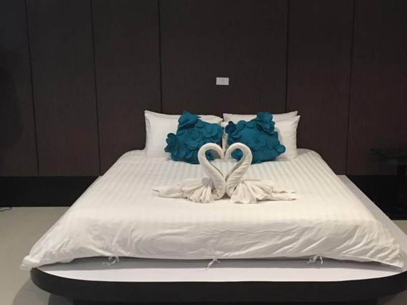 เตียงนอนตกแต่งผ้าขนหนูรูปหงส์ในห้องพักโทนสว่างของ The Rich Hotel อุบลราชธานี