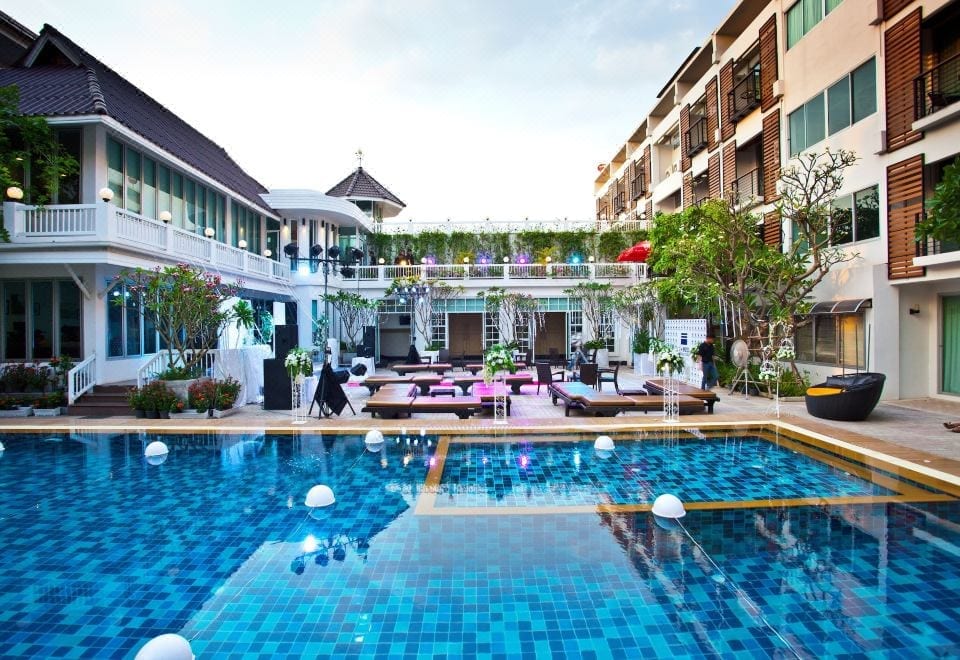 สระว่ายน้ำกลางแจ้งของ Paradise Hotel Udonthani พร้อมสวนและเก้าอี้ริมสระ