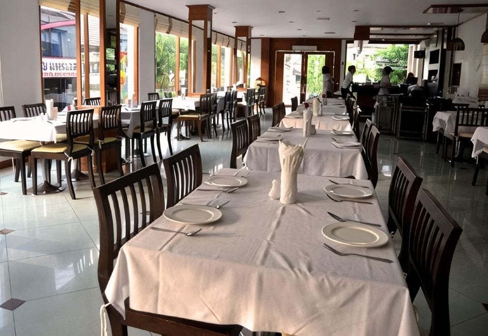 สระว่ายน้ำกลางแจ้งของ President Hotel Udon Thani พร้อมเก้าอี้ริมสระและสวนโดยรอบ